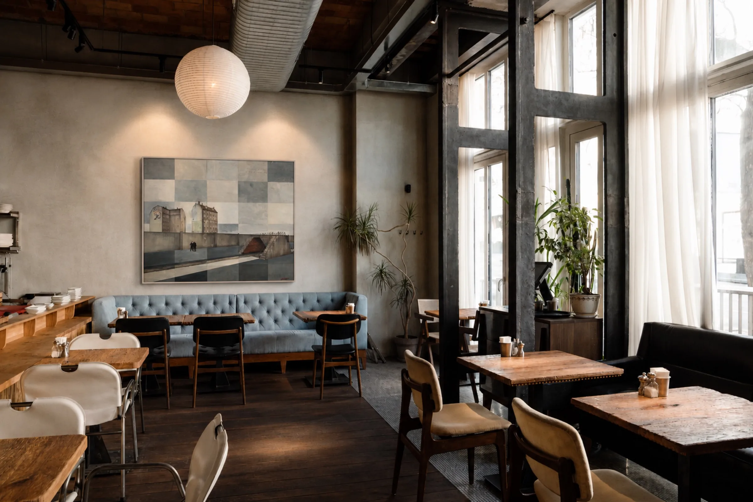 A framed work by Paolo Ventura above banquette seating in a café.